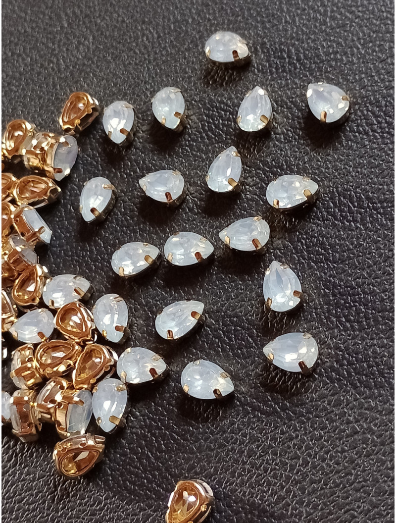 Стразі (акрил) у золотій металевій оправі. Розмір  6*10 мм. Колір білий опал